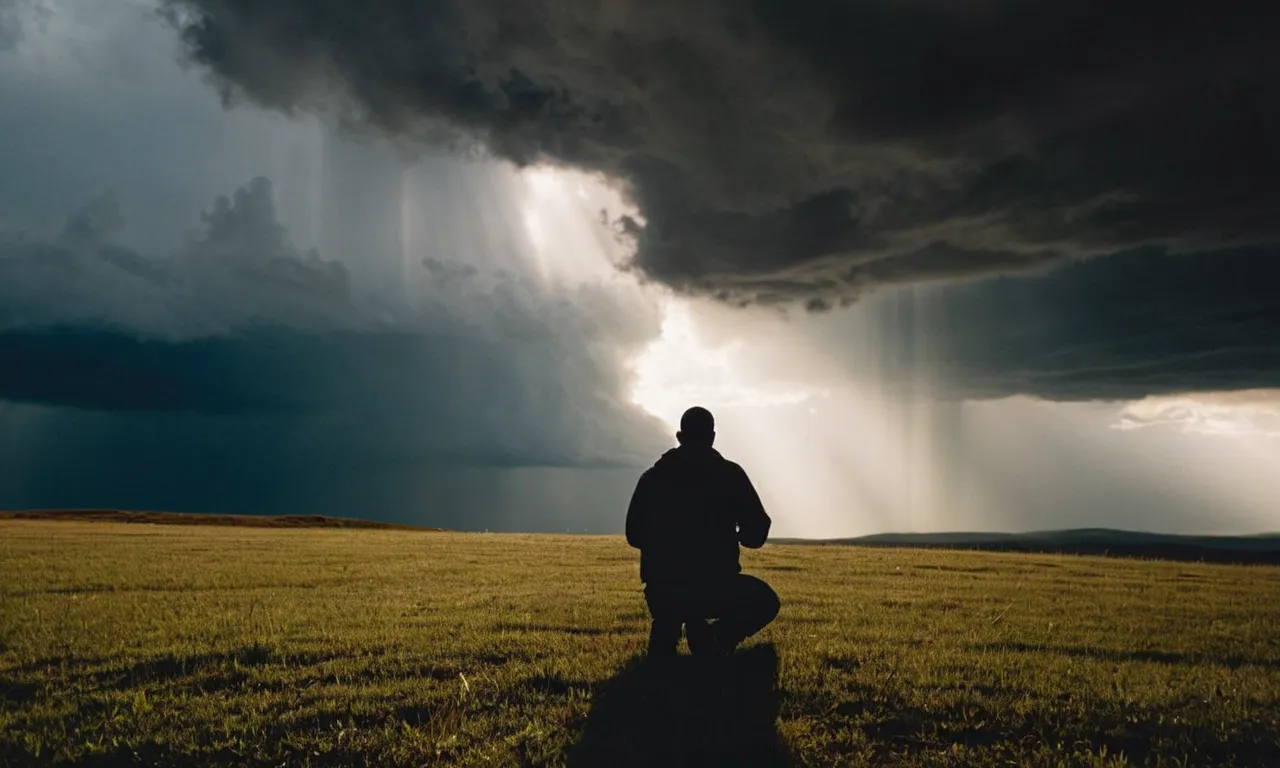 A photo capturing a ray of sunlight breaking through dark storm clouds, illuminating a figure kneeling in gratitude, symbolizing the moment when God answers prayers.