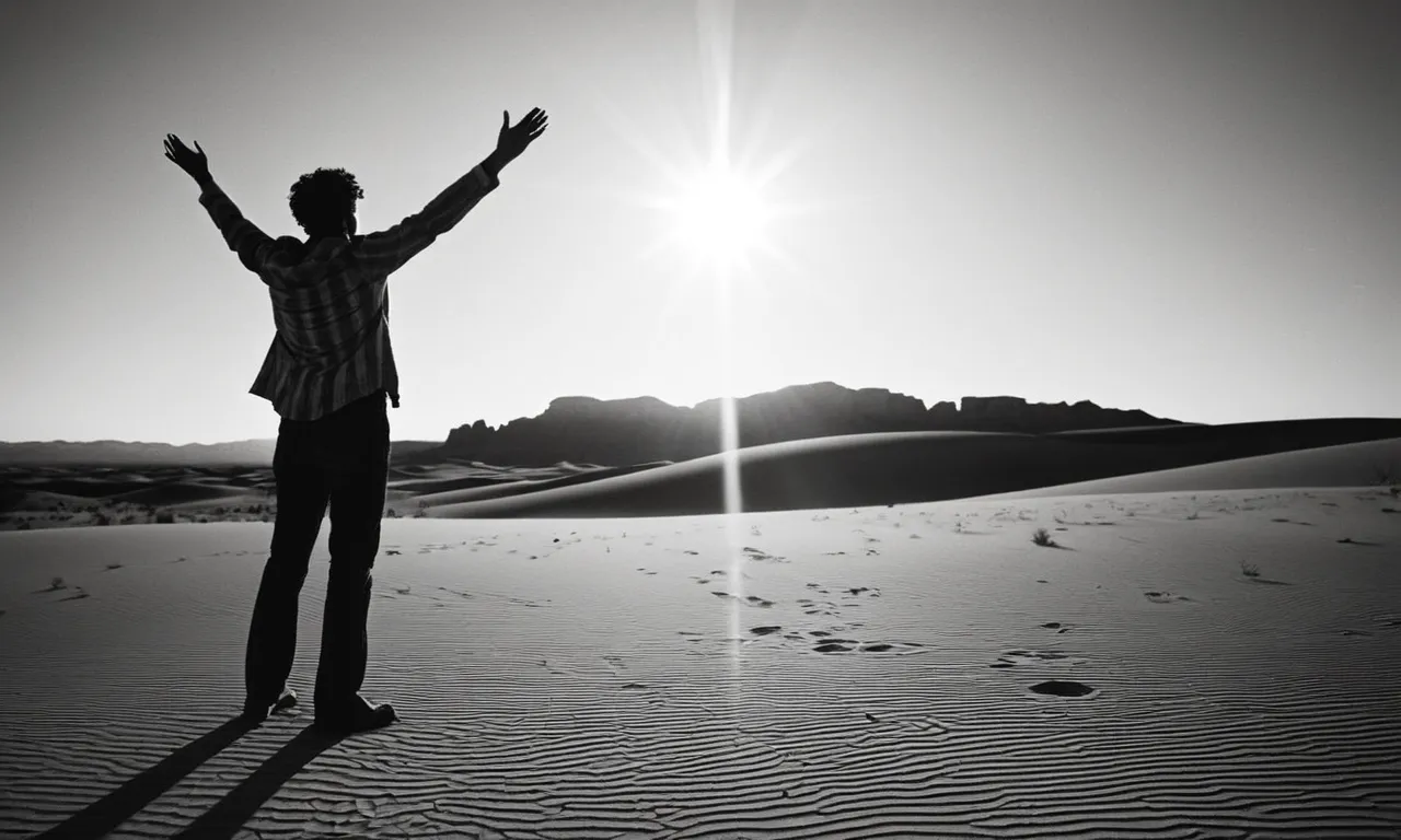 A black and white photograph of a solitary figure standing in a vast desert, their outstretched hands reaching towards the heavens, as the sun sets and casts long shadows.