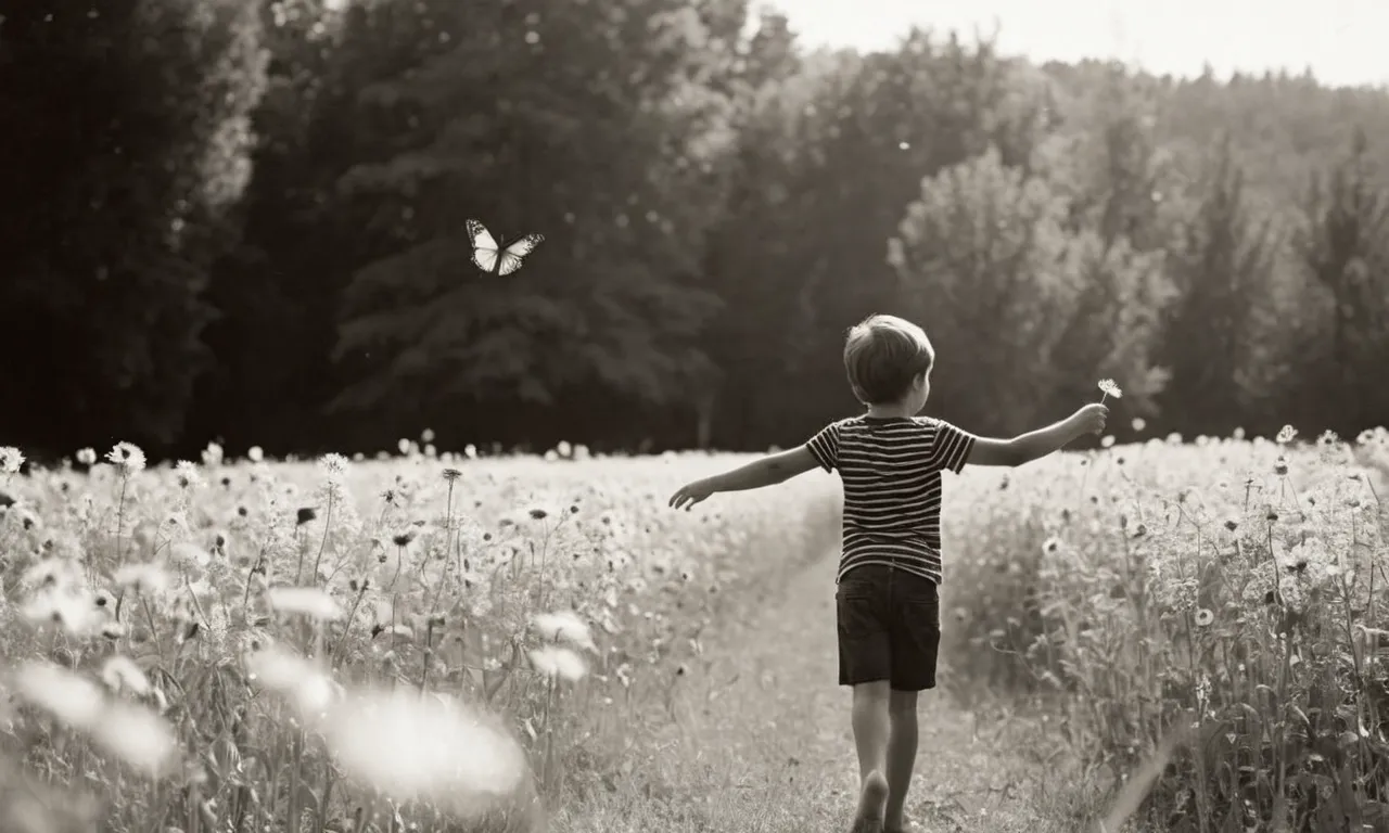 A black and white picture of a young boy, barefoot and carefree, standing in a sunlit field with a butterfly perched on his outstretched finger, capturing the innocence and purity of a time when God was believed to be a child.